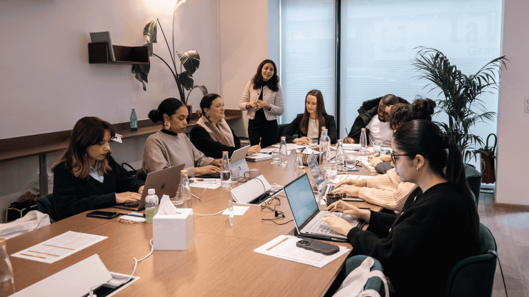 Session de formation en présentiel réunissant des apprenants autour d'une table de travail, animée par une formatrice dans une salle de cours.